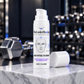 TheLooksMaxxing Daily Peptide Eye Cream pump bottle on a marble plinth in a dark gym